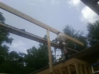 Carpenter setting a ridge beam over a new addition frame in Mc Calla