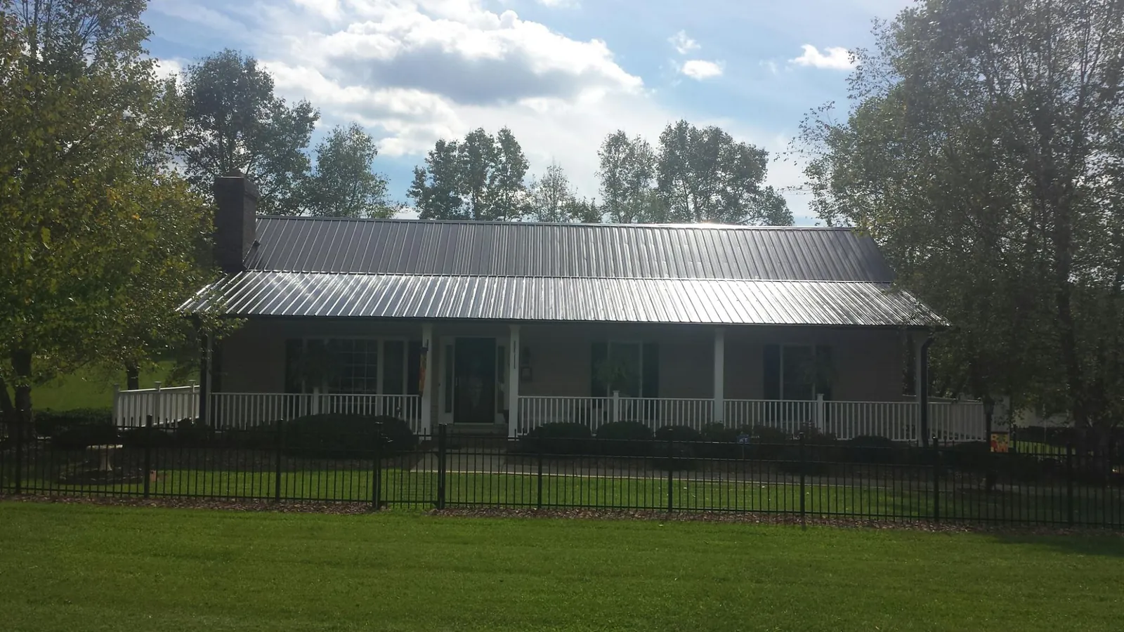 Gray metal roof on a brick ranch with a full width front porch — Gutter Guard Installation work by our crew in Mc Calla