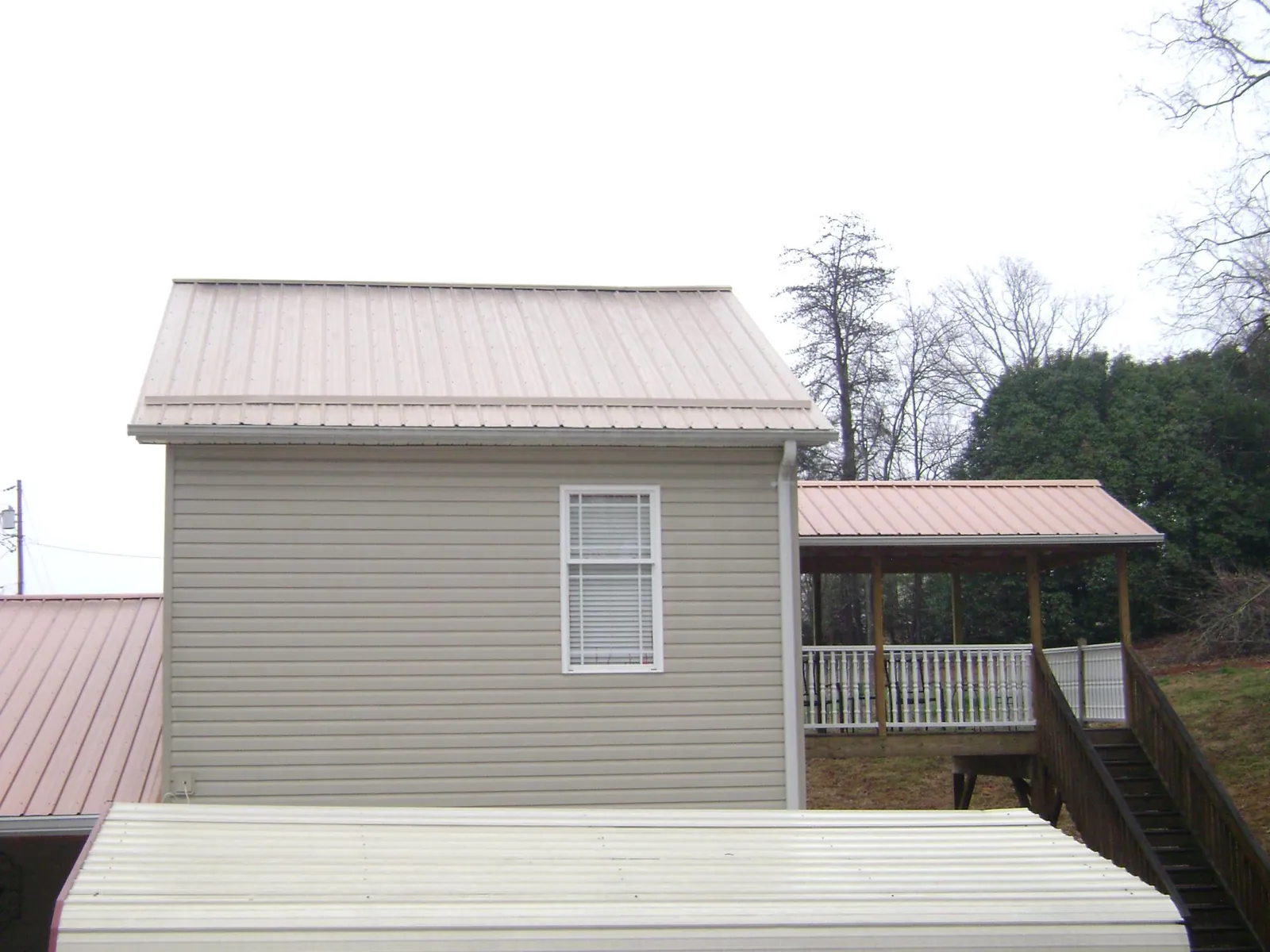 Tan metal roofs on a two story addition and attached porch, from a Roof Replacement job in Mc Calla