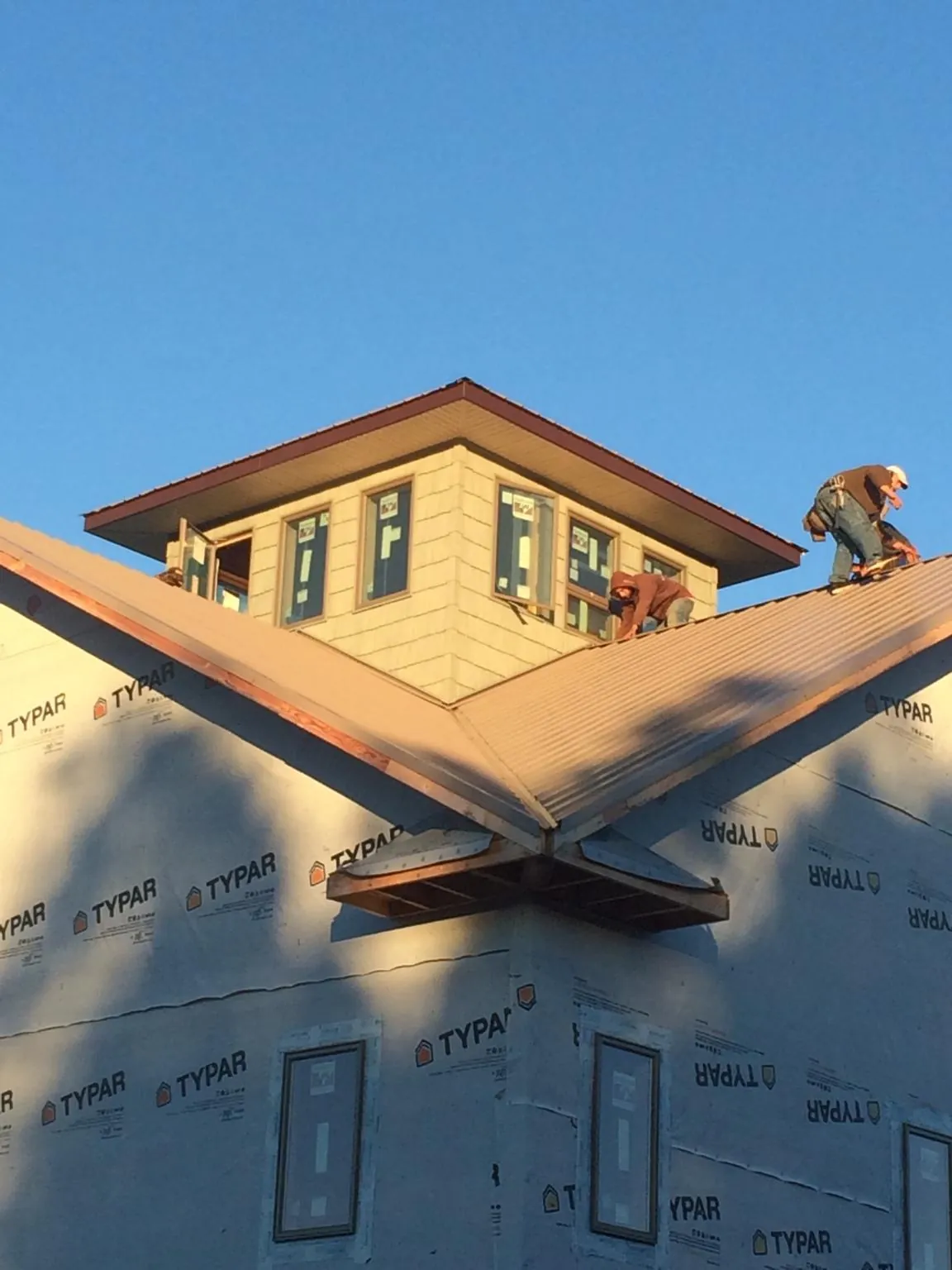 Roofers working around a rooftop cupola on a new metal roof at sunset — Roof Waterproofing in Mc Calla by Roofing Brothers